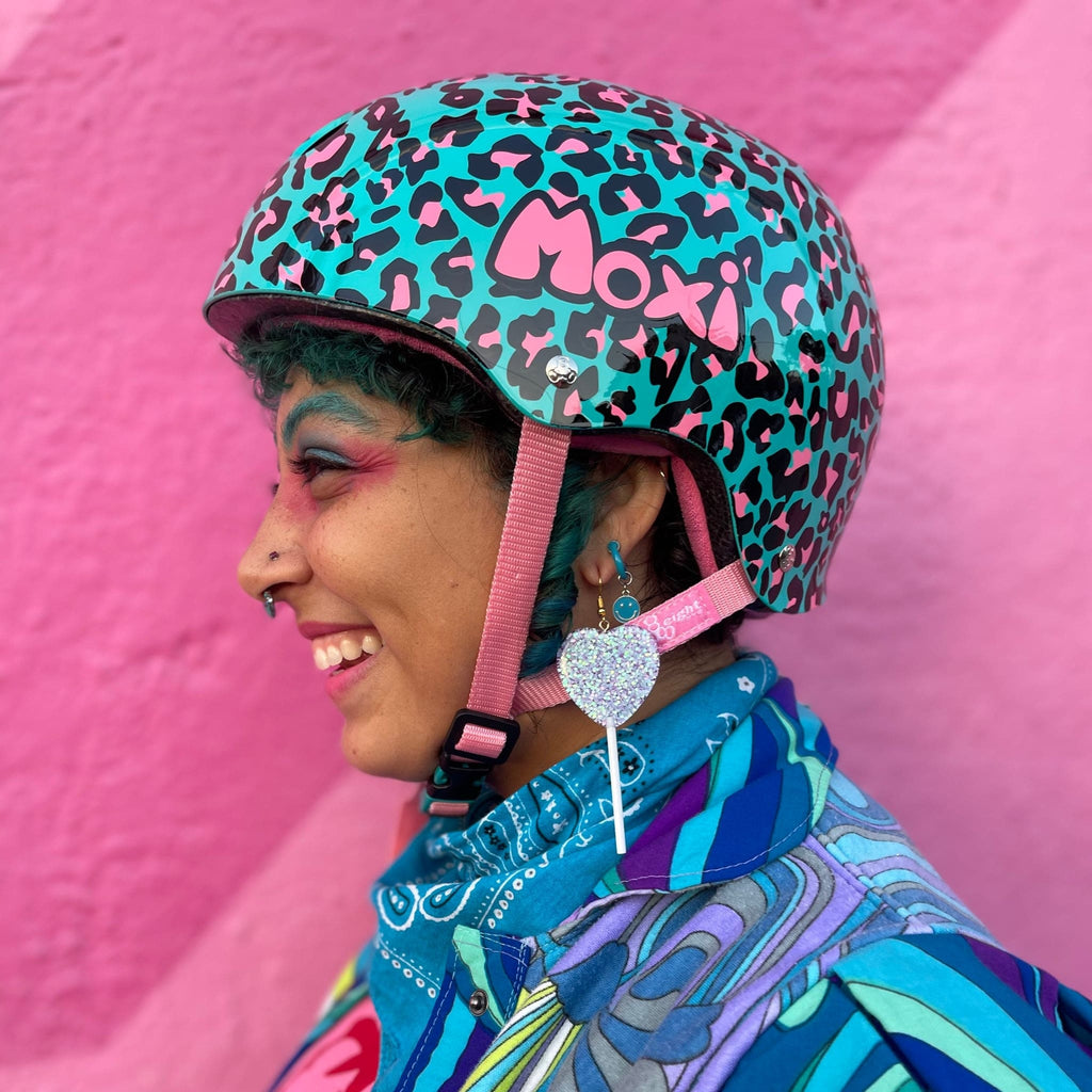 Side view of Moxi Helmet in Blue Leopard. The color of the helmet has the base of blue with leopard print of black and pink spots.