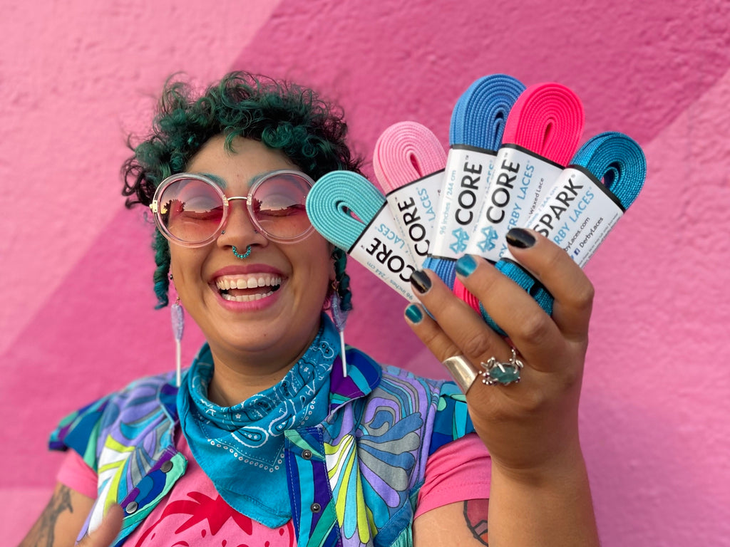 Smiling skater wearing Malibu sunnies while holding 5 Derby Laces.