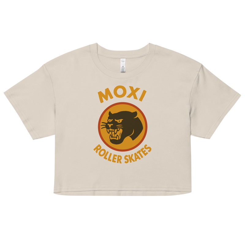 Vintage white Moxi crop top with short sleeves, featuring a bold vintage-style graphic of a yellow and orange panther logo and “MOXI Roller Skates” text on the front.