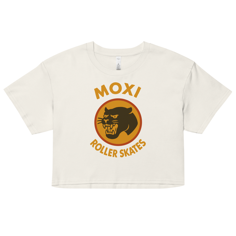 White Moxi crop top with short sleeves, featuring a bold vintage-style graphic of a yellow and orange panther logo and “MOXI Roller Skates” text on the front.