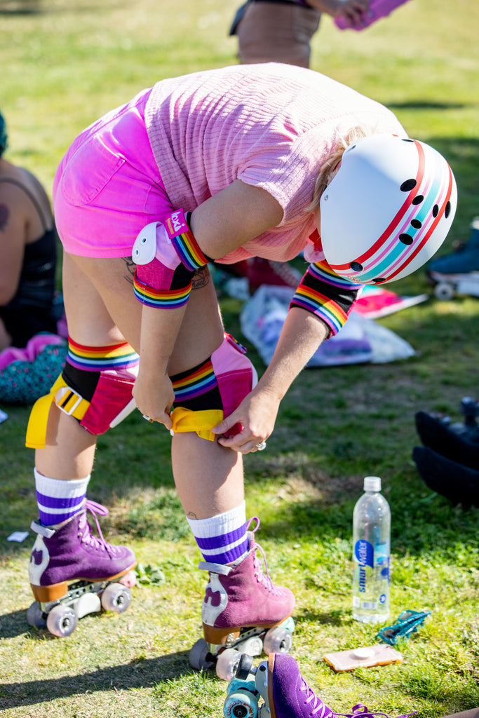 Skater putting on skate pads wearing Stripey helmet.